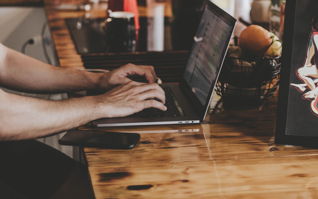 Hands typing on a keyboard in a cafe. You cannot see the person's face.