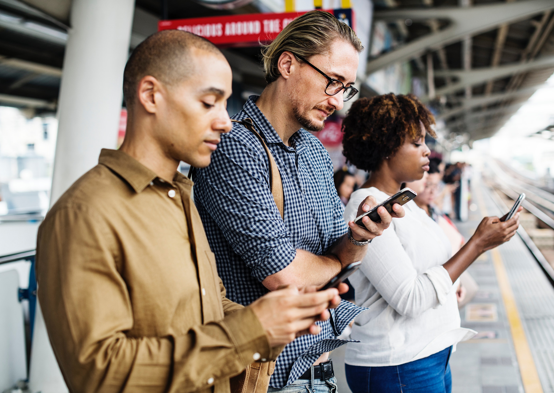 Three passengers order taxi's from their mobile device at an airport curb.