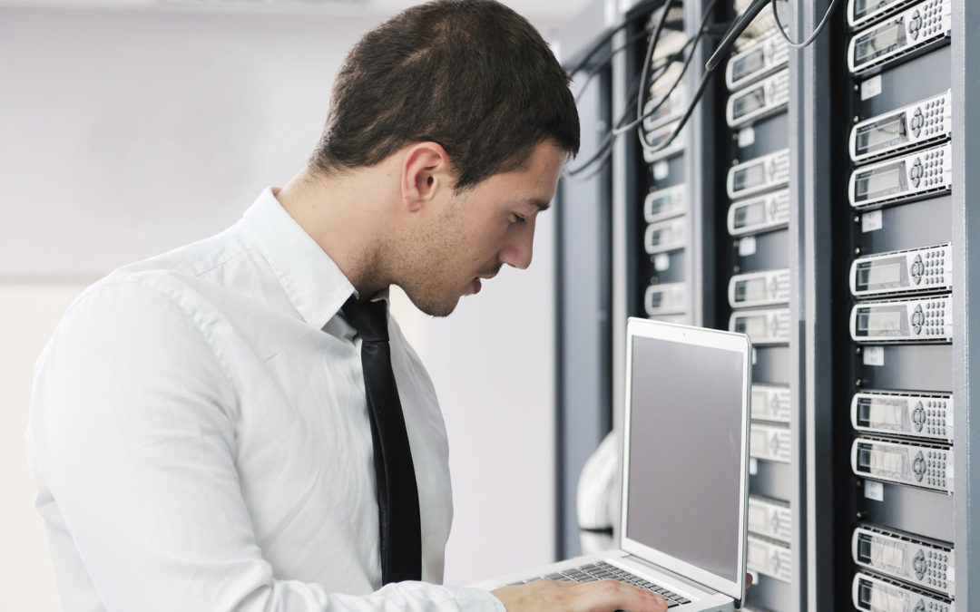 Business man holding a computer by computer servers.