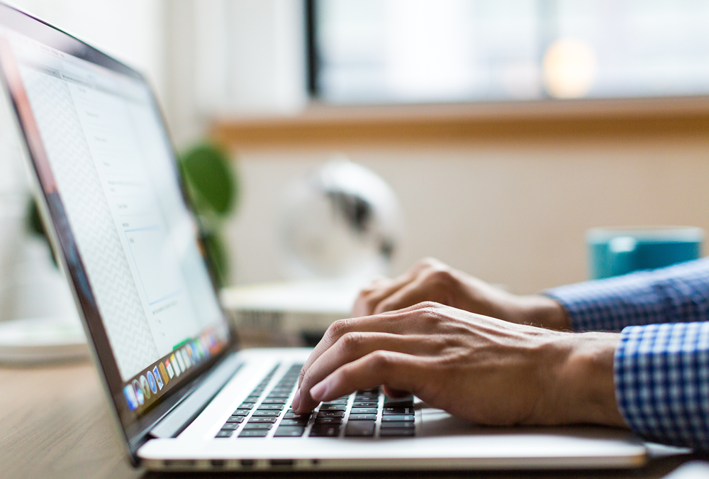 A pair of hands typing on a laptop. You cannot see the person's body or face.