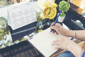 Hand copying a calendar into a notebook, symbolizing the streamlined design thinking consulting process offered by Pivotree.