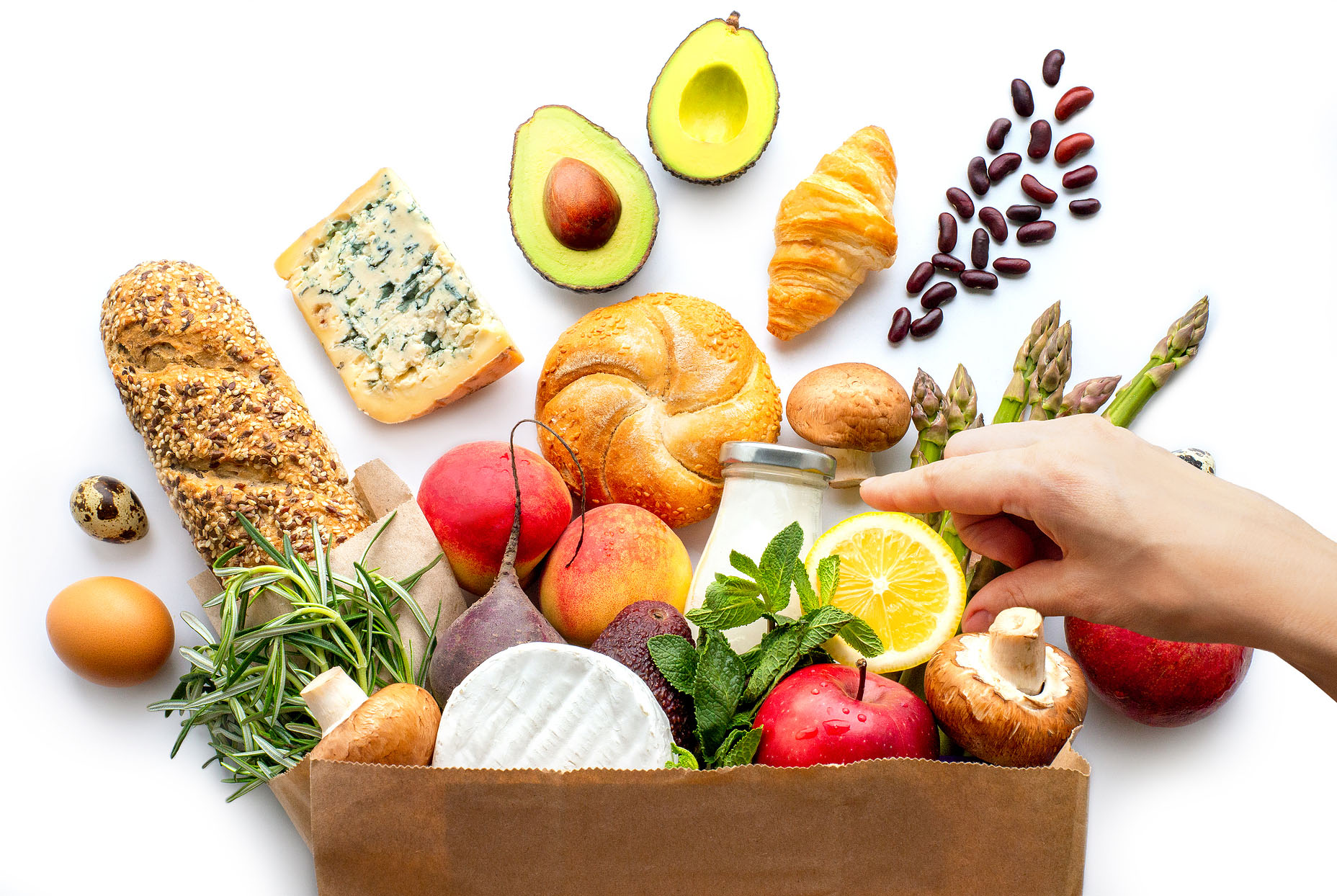 Grouping of breads and vegetables in a bag with a hand touching them