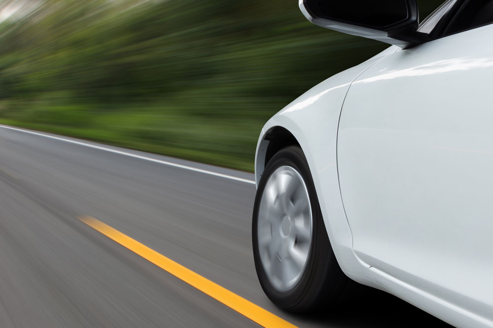 fast white car driving down a blurry rural road